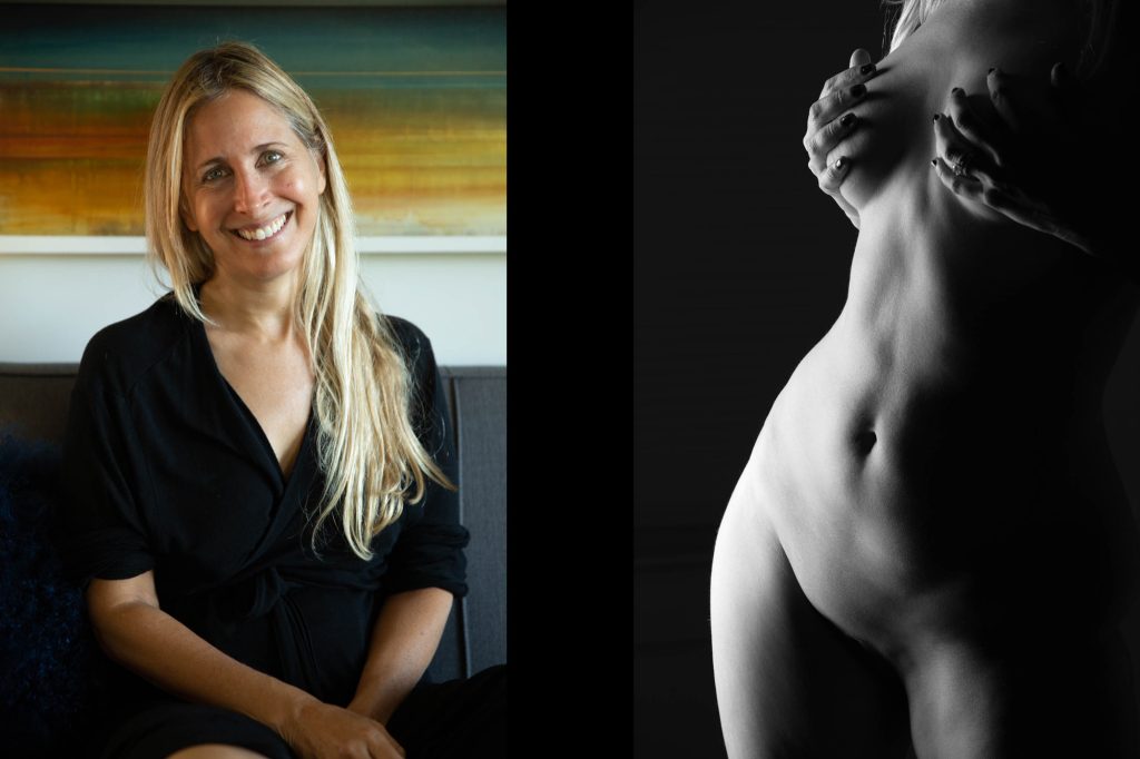 Artistic female figure photo shoots for every day women. This before and after features a client with long blonde hair in soft, diffused lighting blending warm earth tones and cool neutrals. On the left, she beams with a wide smile while seated comfortably on a gray sofa, hands resting in her lap, wearing a loose black wrap blouse amid a colorful abstract wall painting in sunset hues. On the right, in black-and-white, she poses confidently in three-quarter view with arms crossed modestly over her torso, her form illuminated by high-contrast shadows that accentuate gentle contours and serene expression against a minimalist dark background.